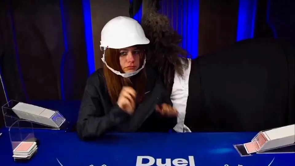 Annika in a white hard hat dealing on the blue Duel blackjack felt