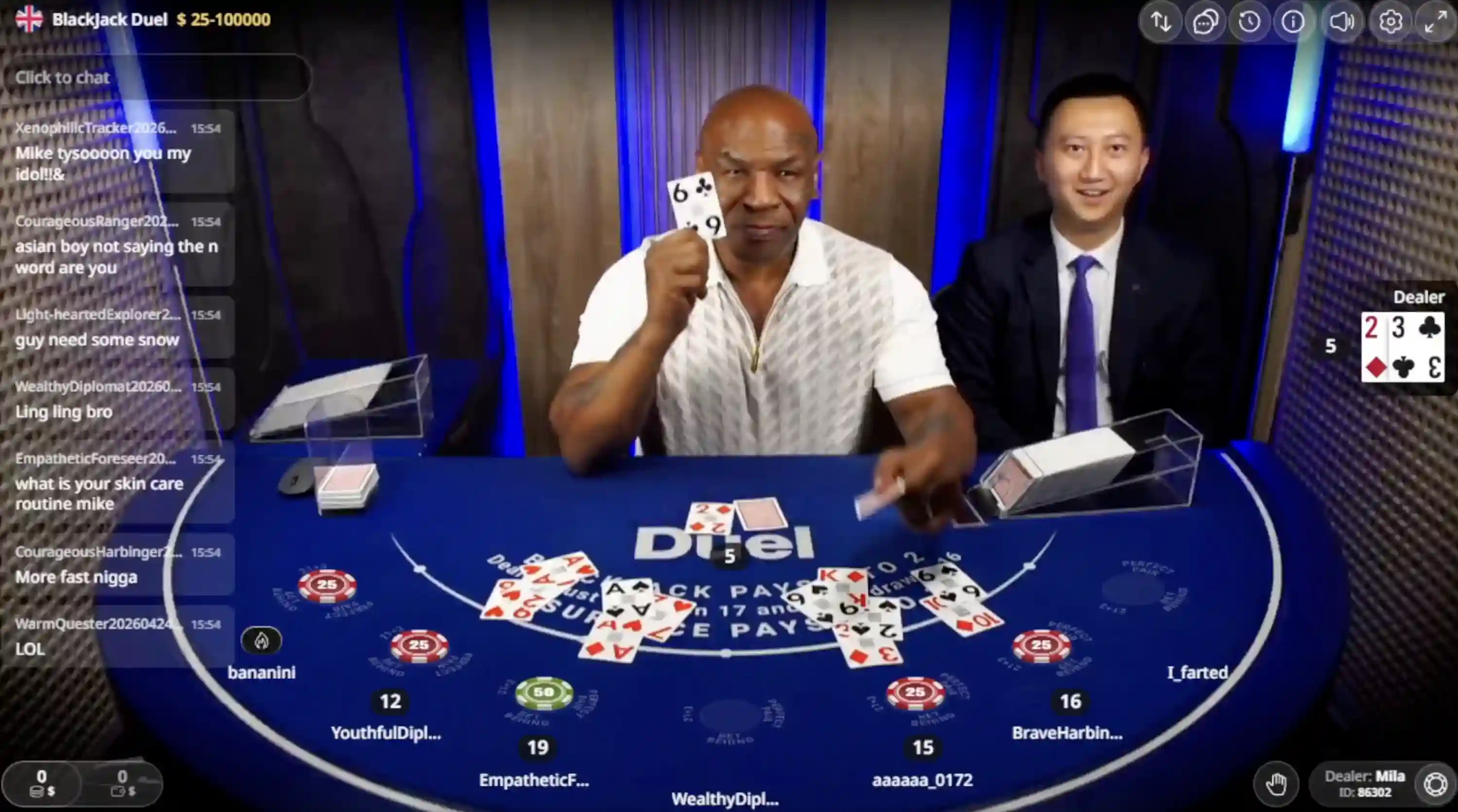 Mike Tyson live dealer at Duel Online Casino Blackjack Duel table holding the six of clubs on branded felt with $25 to $100,000 crypto limits and live chat overlay